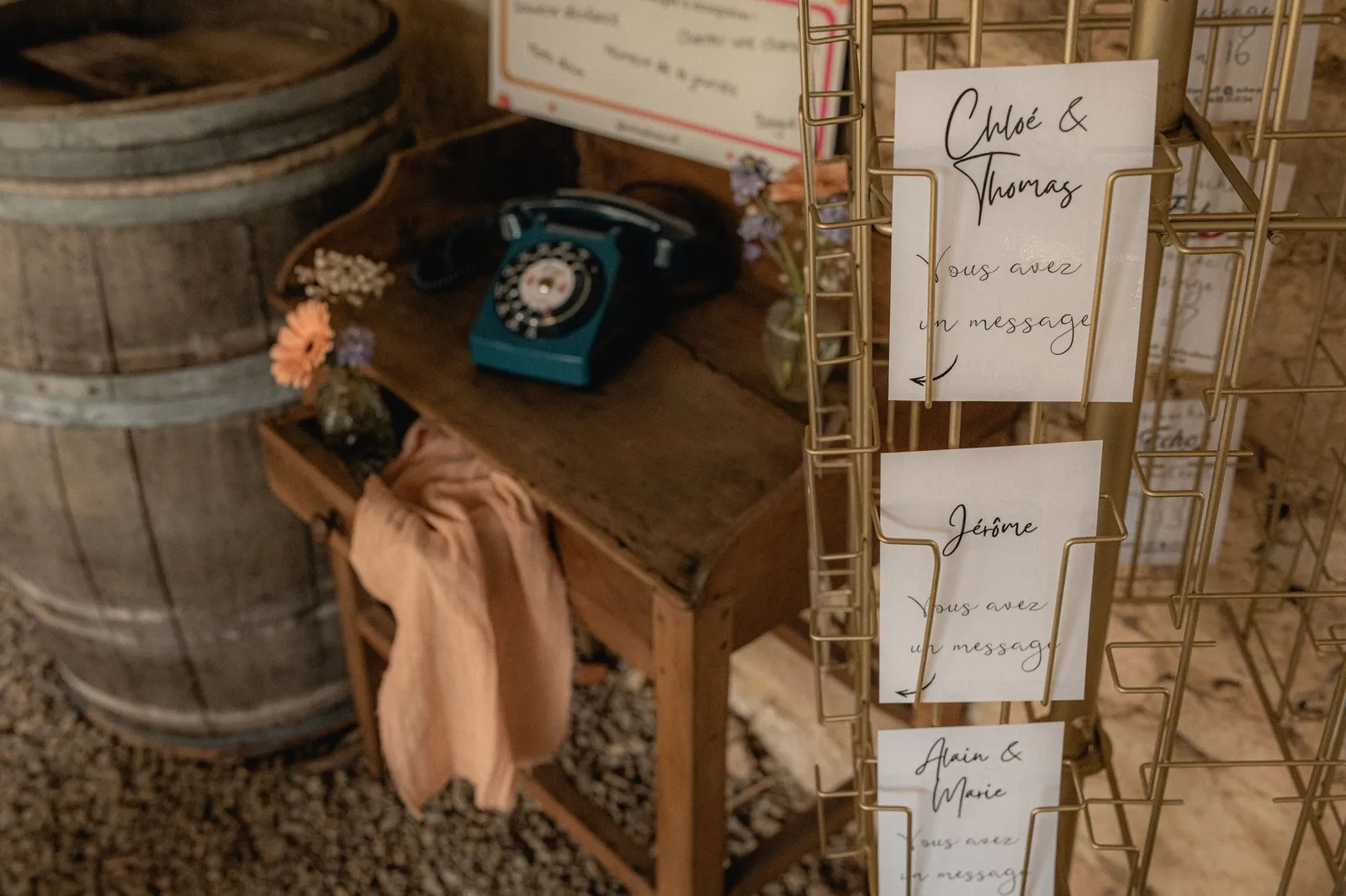 Téléphone vintage bleu HearMe sur un meuble en bois lors d'un mariage, à côté d'un présentoir de cartes « Vous avez un message »