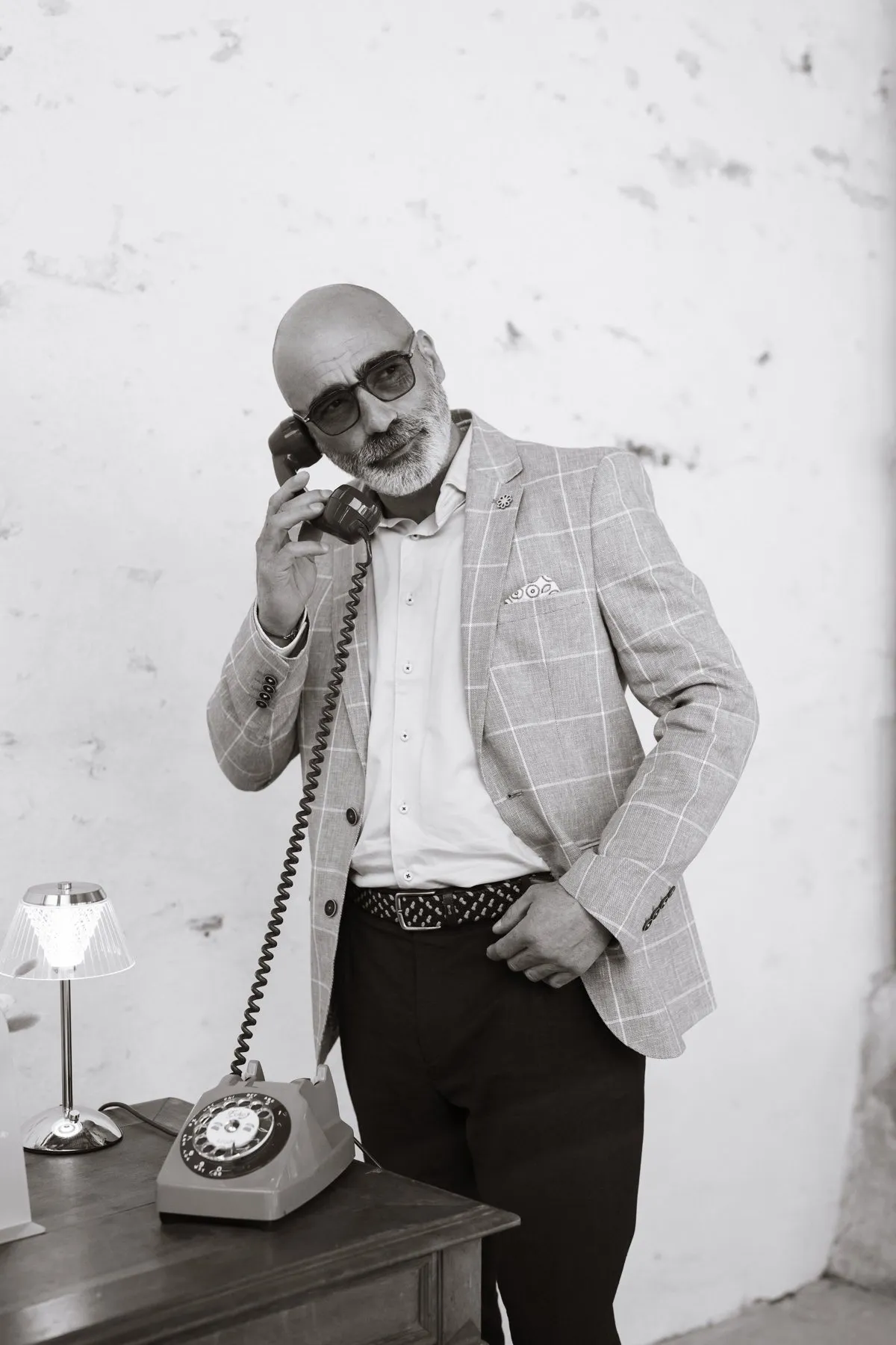 Homme en veste à carreaux au combiné d'un téléphone vintage gris, photo en noir et blanc