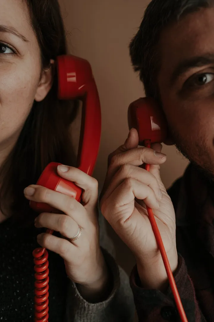A couple listening to two red handsets